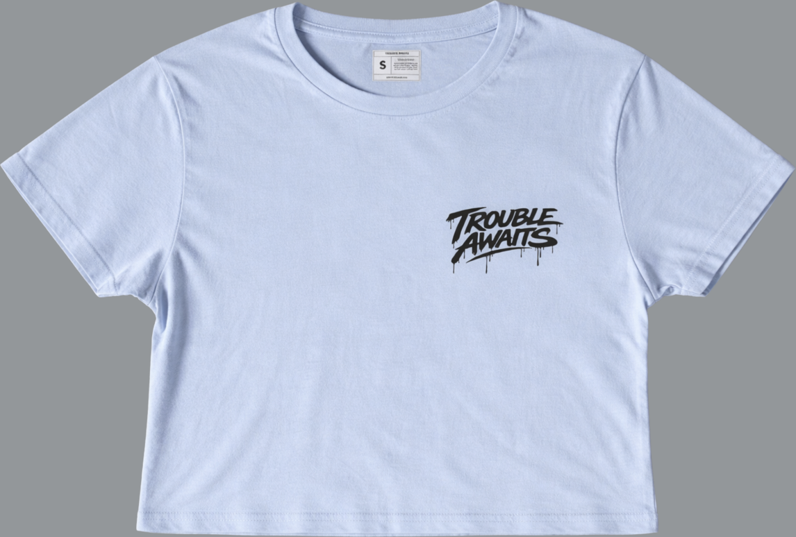 Front of light blue cropped t-shirt featuring small black Trouble Awaits logo in dripping graffiti style on chest