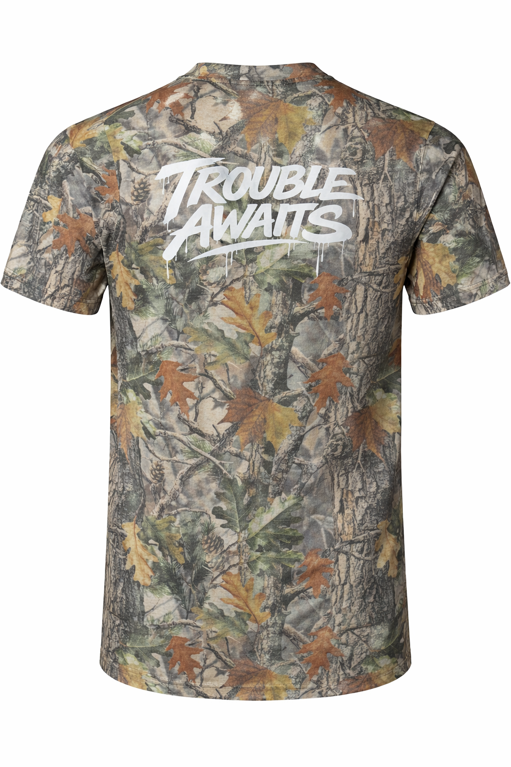 A back view of an oversized, boxy short-sleeve T-shirt displayed flat against a neutral white background. The shirt features a realistic woodland camouflage pattern made up of tree bark textures, branches, and scattered leaves in shades of green, brown, tan, and muted gray.

Centered across the upper back is a large white “Trouble Awaits” graphic in a bold, graffiti-style script. The lettering includes dripping paint details beneath several strokes, giving it a street-art-inspired look 